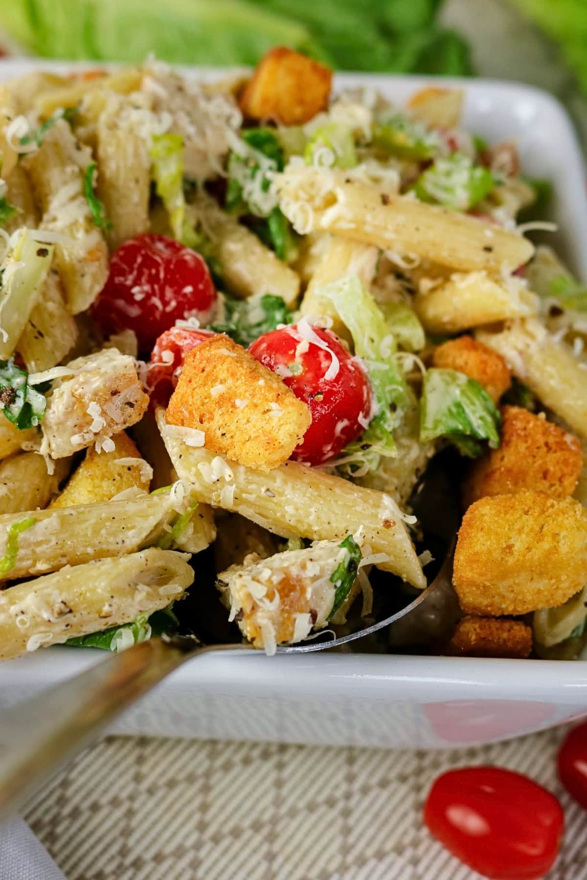 Pasta salad with penne, croutons, cherry tomatoes, lettuce, and grated cheese.