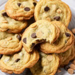 A plate of chocolate chip and peanut butter chip cookies, one with a bite taken out.