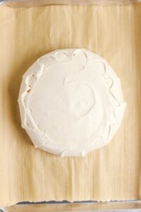 Round baked meringue on parchment paper, viewed from above.