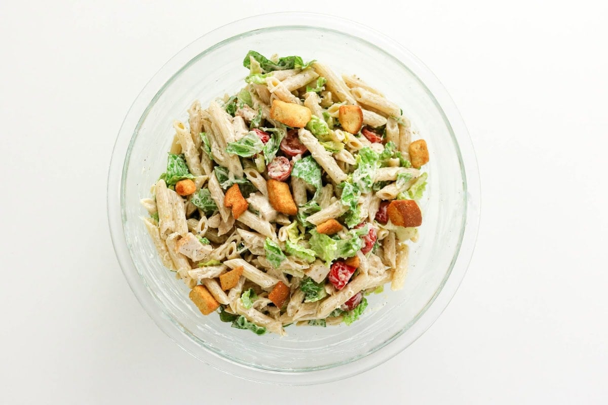 Bowl of pasta salad with lettuce, tomatoes, croutons, and creamy dressing.