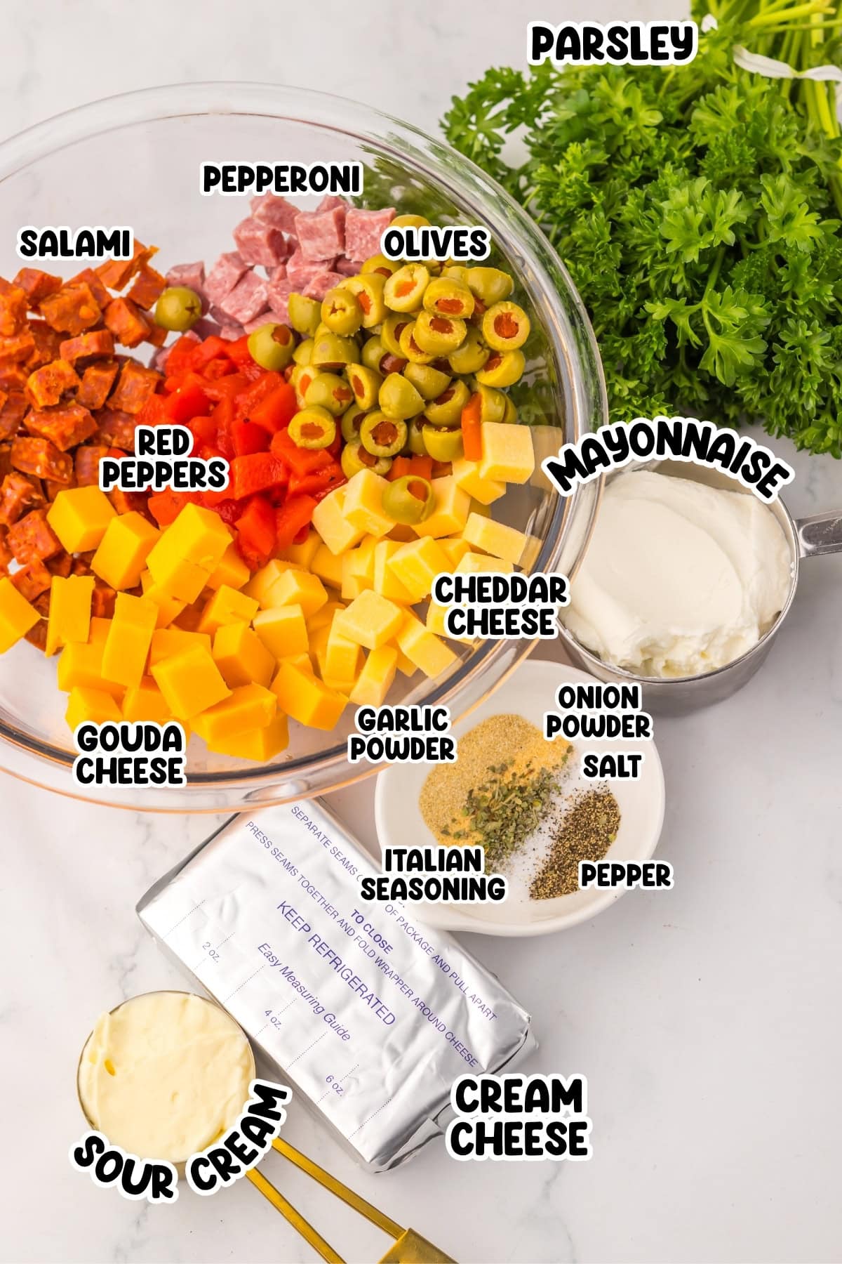 Ingredients for a dip including meats, cheeses, spices, and fresh parsley are displayed.
