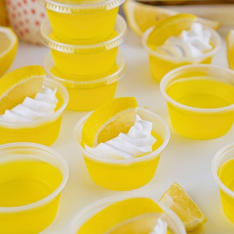 Small cups of yellow gelatin topped with whipped cream and lemon slices.