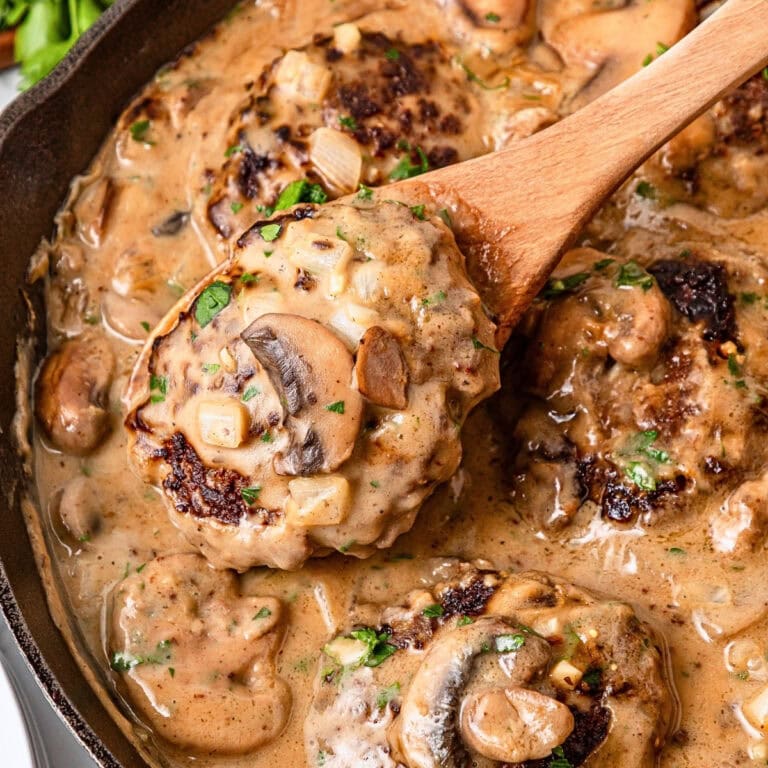 Salisbury steak patties in creamy mushroom gravy, served in a skillet.