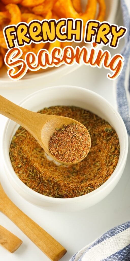 A bowl of French fry seasoning with a wooden spoon above curly fries.