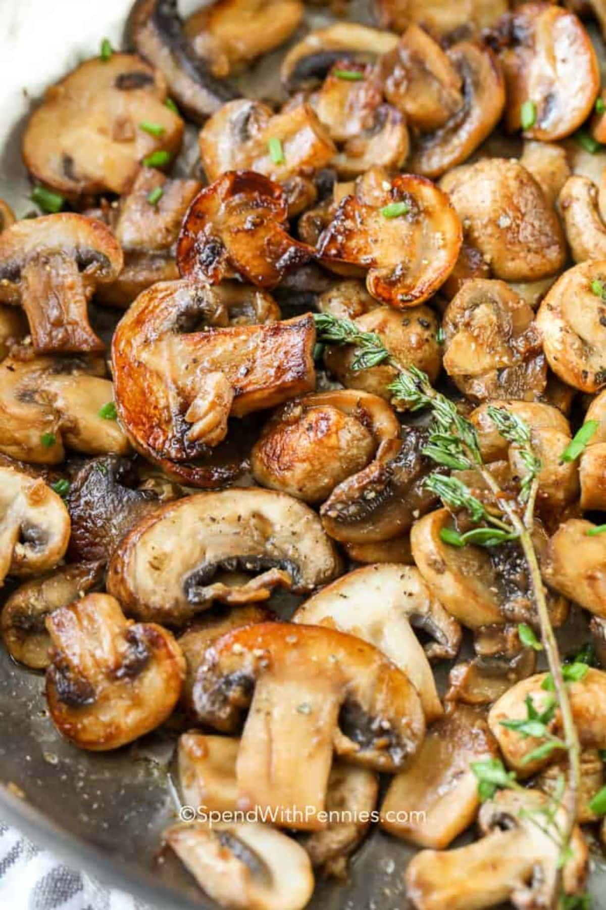 Sautéed sliced mushrooms with herbs in a pan.