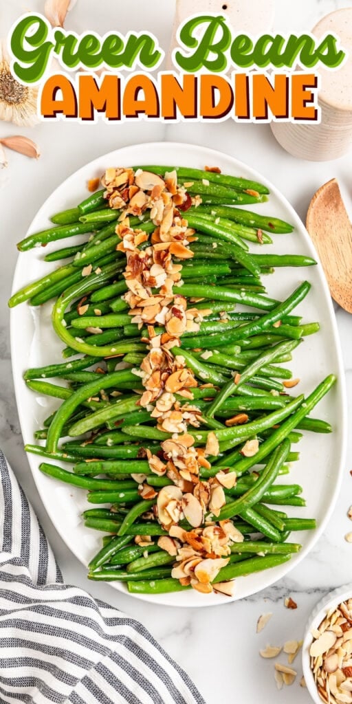 Green beans topped with toasted sliced almonds on a white oval platter.