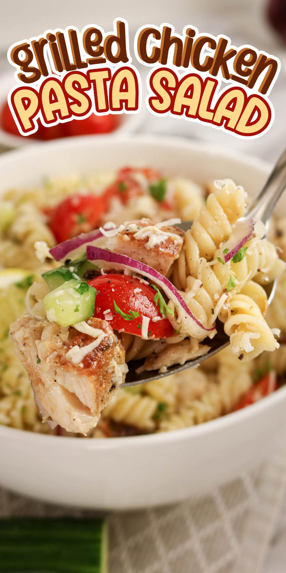 A fork holds grilled chicken pasta salad above a bowl, topped with veggies and cheese.
