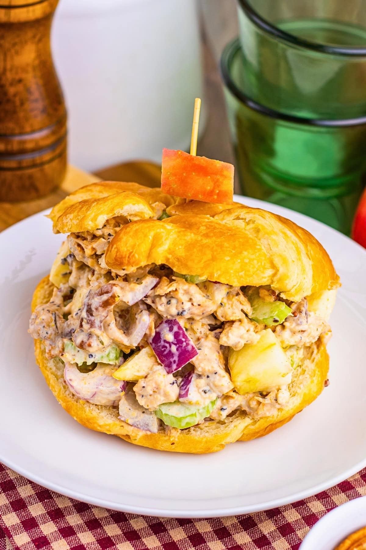 Chicken salad croissant sandwich with apples and celery on a white plate.