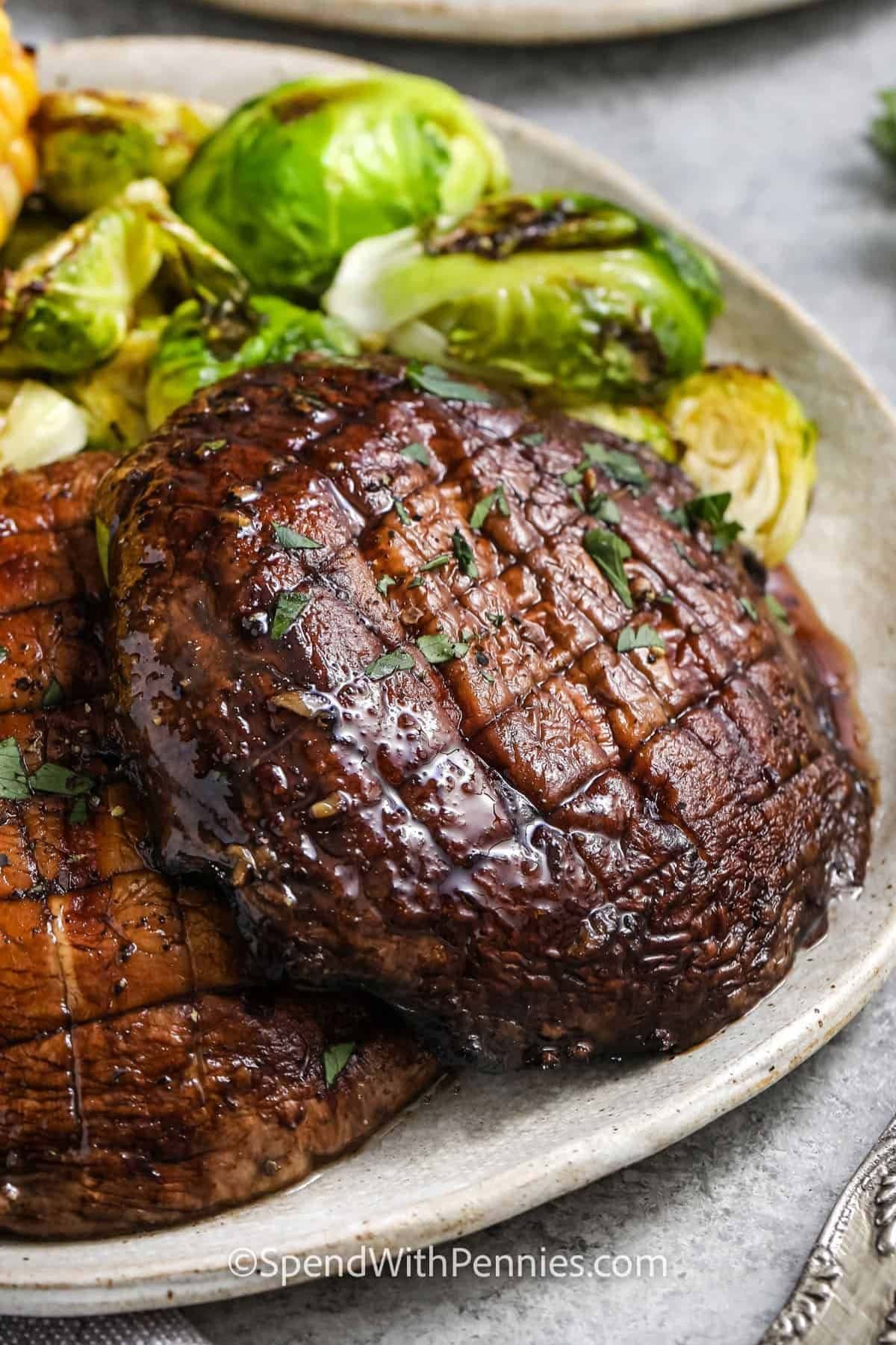 Two grilled portobello mushroom caps with brussels sprouts on a plate.