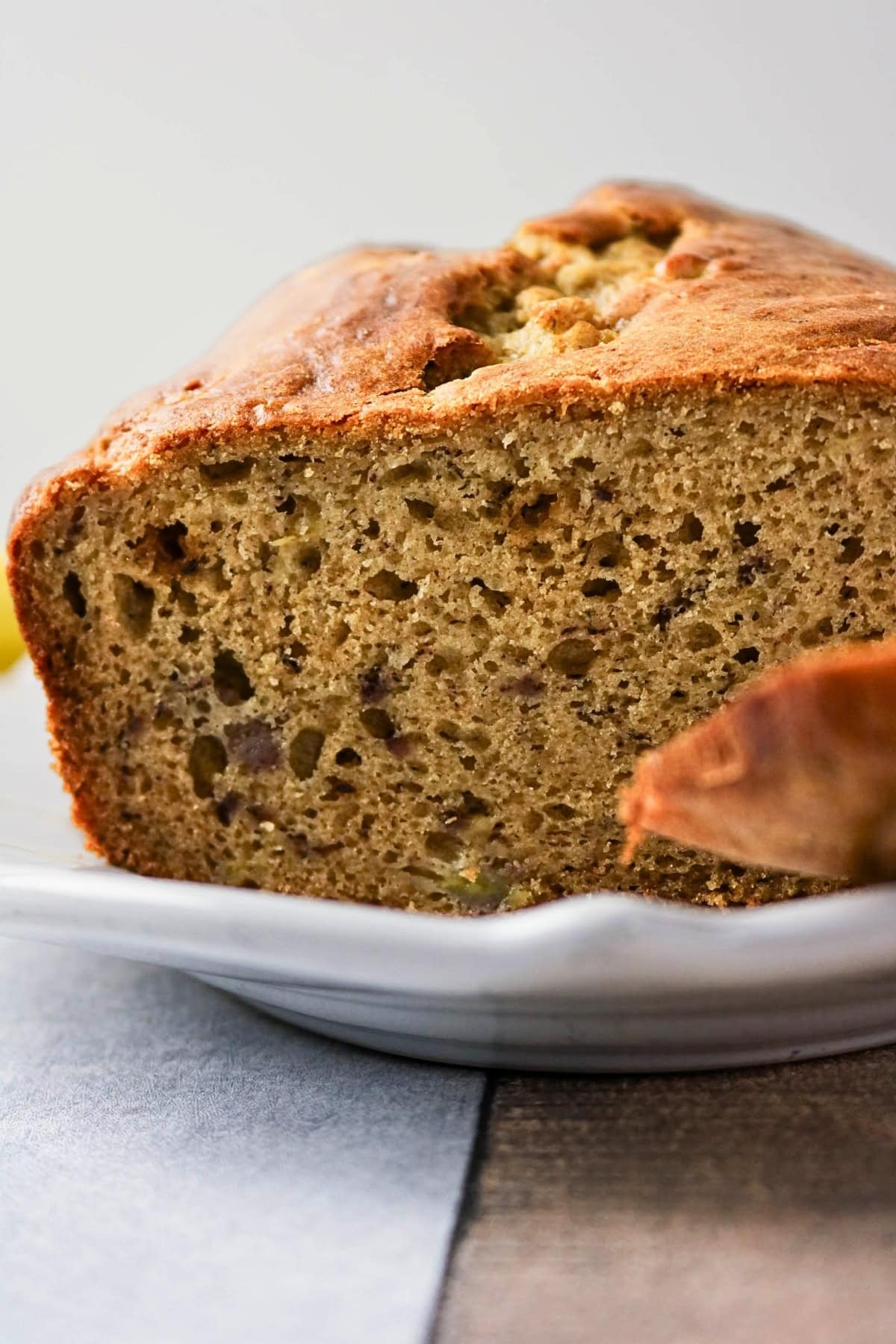 A close-up of a sliced loaf of banana bread on a white plate.