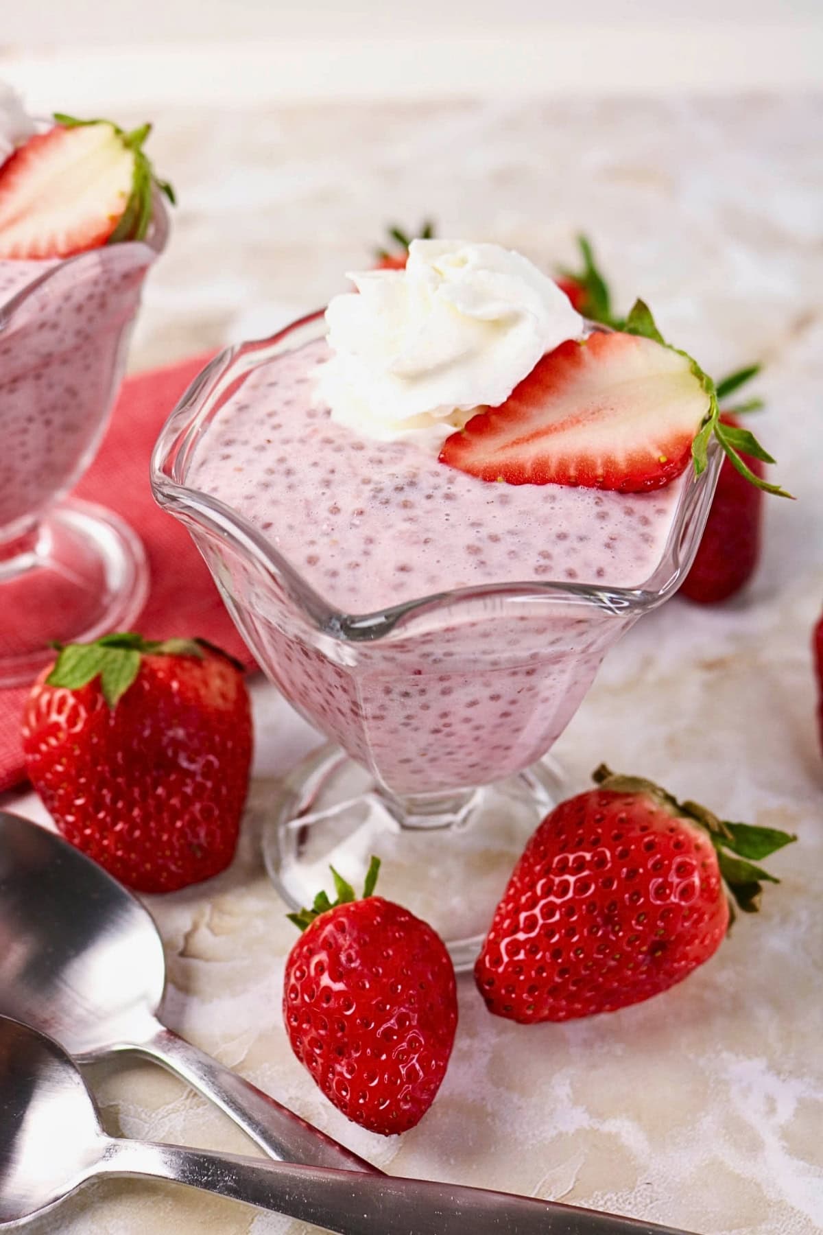 Strawberry chia pudding topped with whipped cream and a strawberry slice.