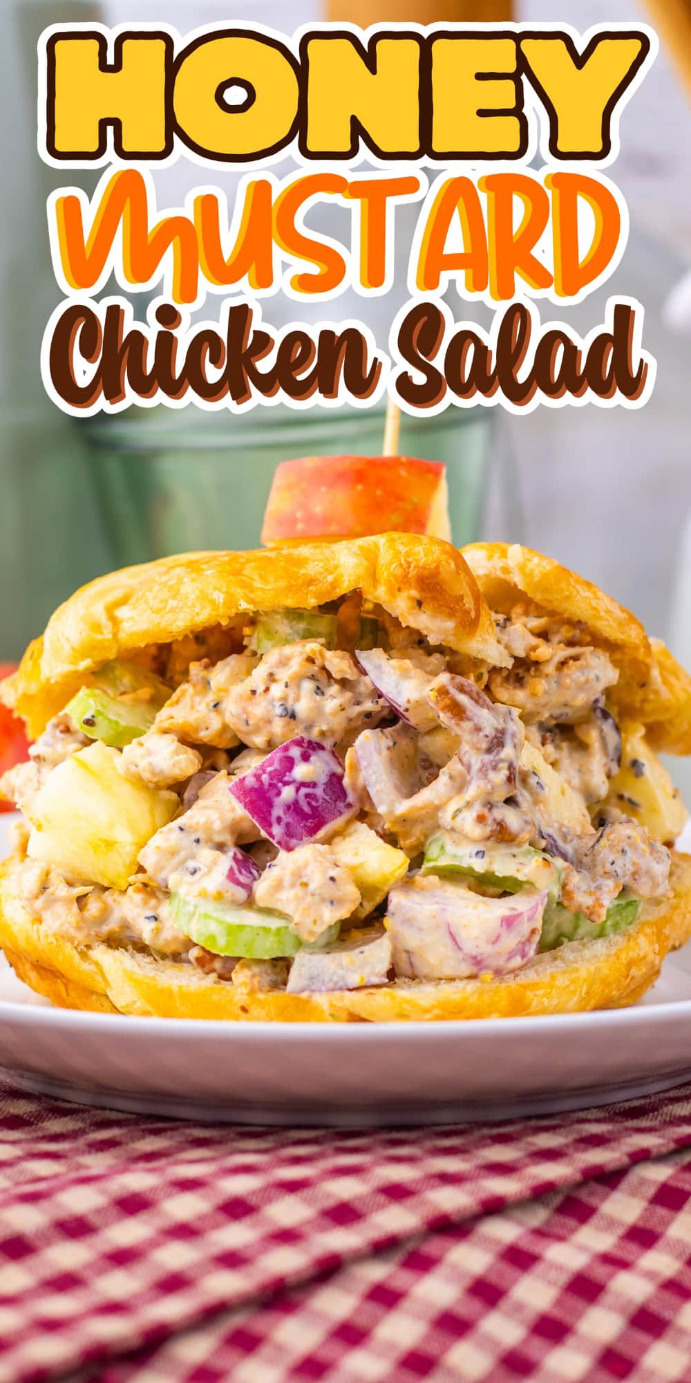 Honey mustard chicken salad sandwich on a croissant, with apple slice garnish.
