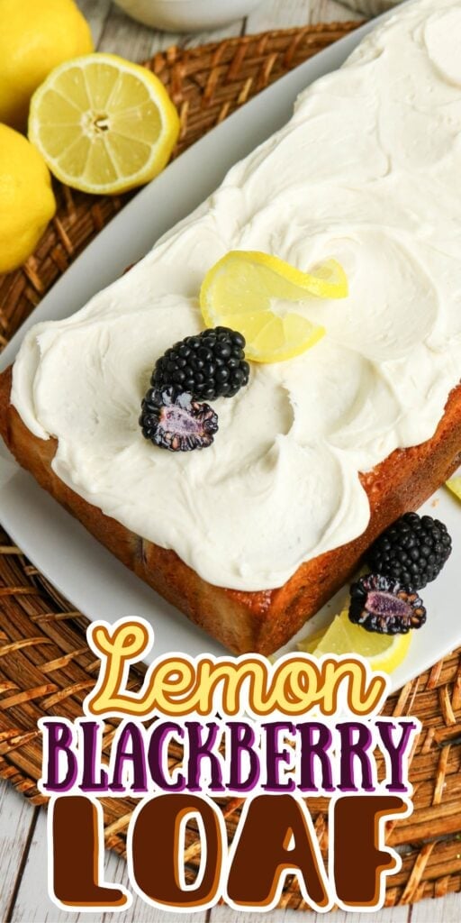 Lemon loaf topped with blackberries and a lemon slice, with lemons nearby.