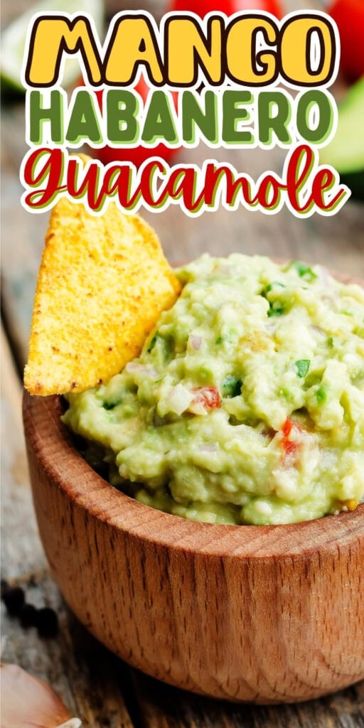 A wooden bowl of guacamole with a tortilla chip.