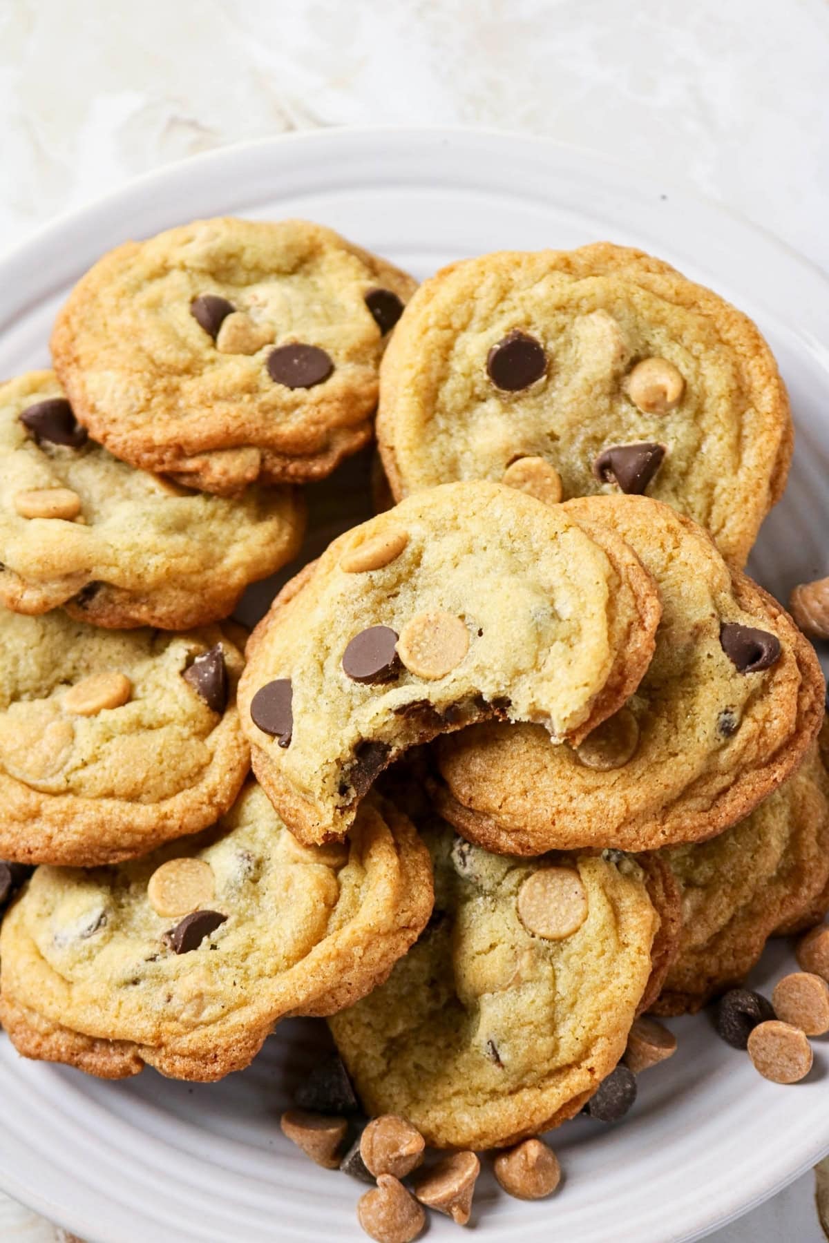 A plate of chocolate chip and peanut butter chip cookies, one with a bite taken.