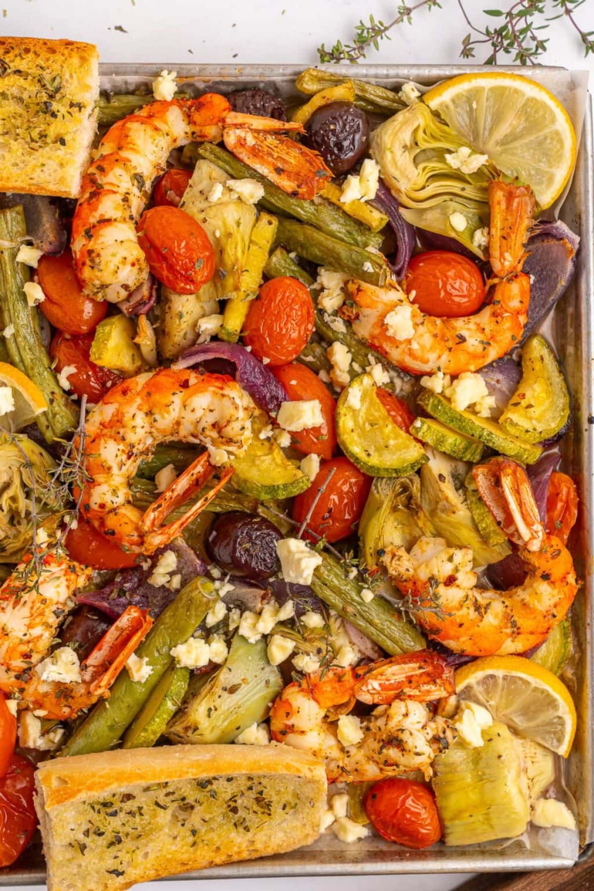 Sheet pan dinner recipes with shrimp, tomatoes, artichokes, olives, and lemon.