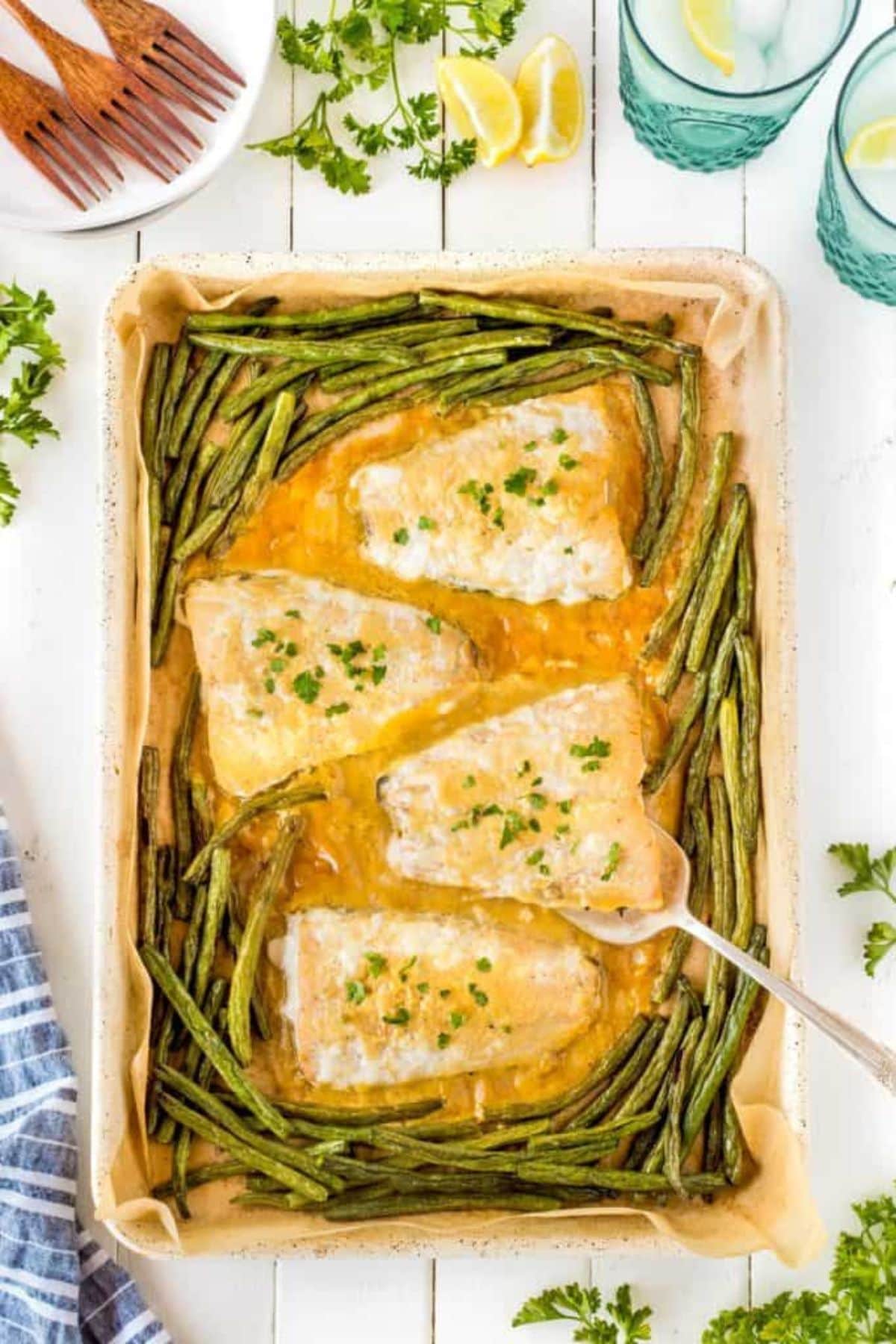 Sheet pan dinner recipes: Baked fish fillets with green beans, garnished with parsley.