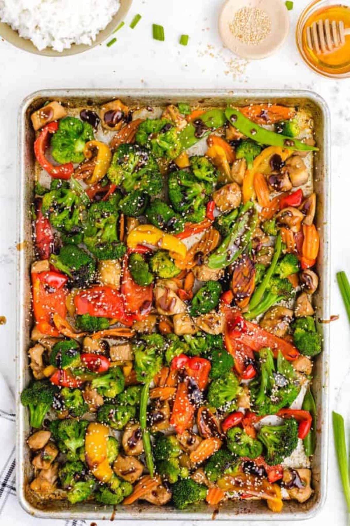 Sheet pan dinner recipes featuring colorful roasted veggies and chicken with sesame seeds.