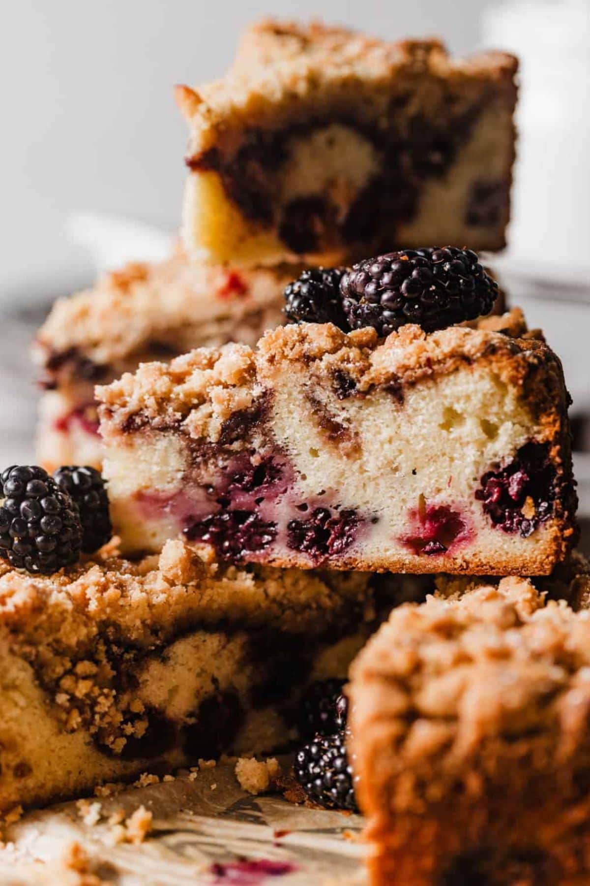 Slices of crumb-topped blackberry coffee cake stacked with fresh blackberries.