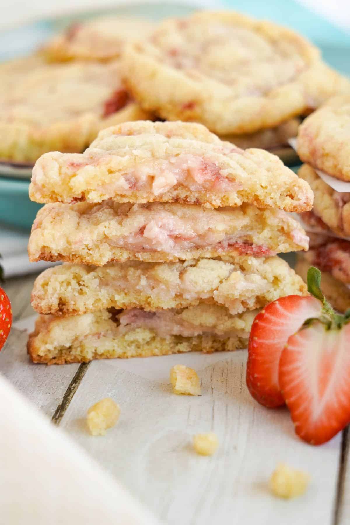 Stack of strawberry cookies with visible chunks, next to fresh sliced strawberries.