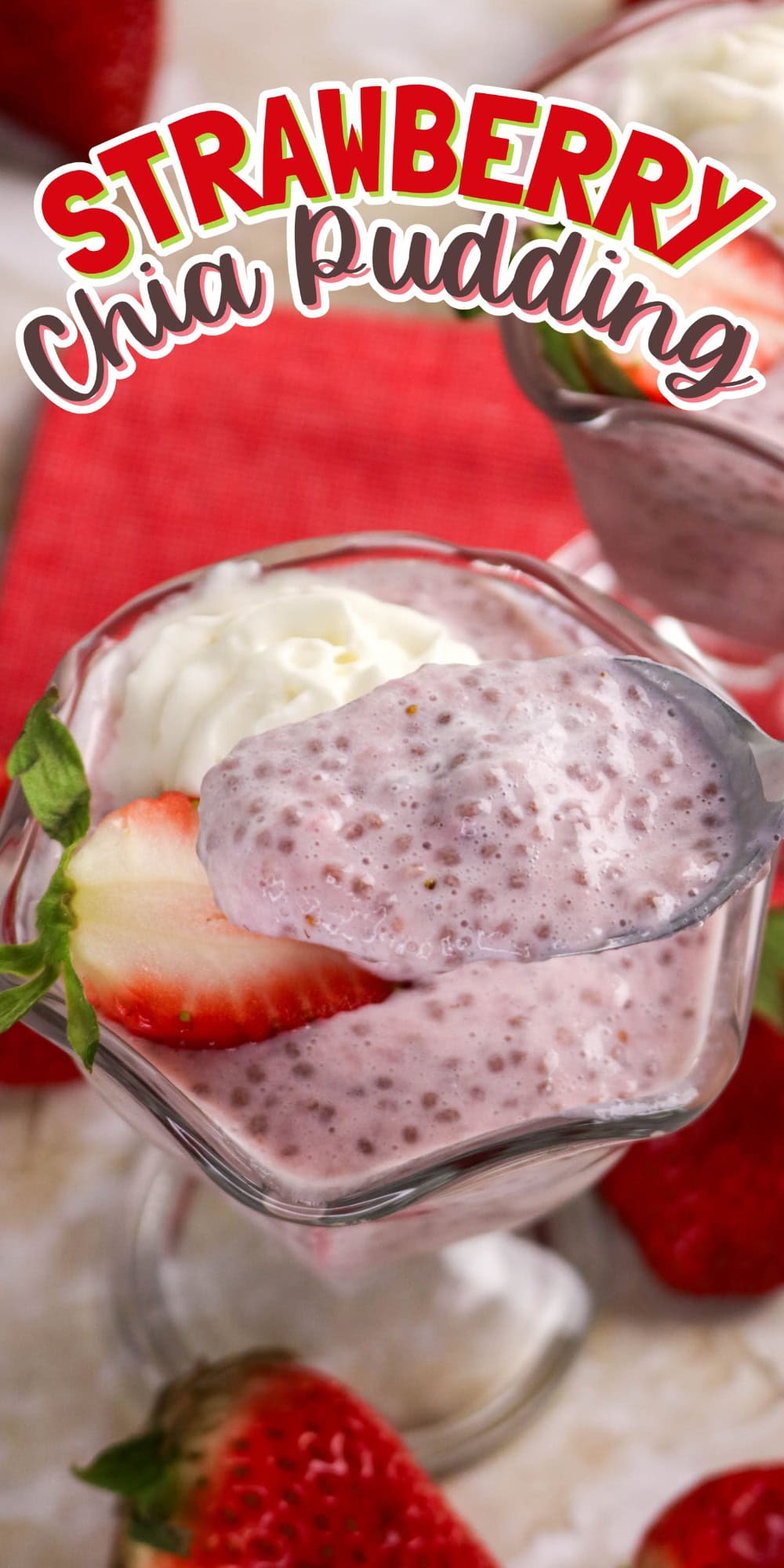 Glass of strawberry chia pudding topped with whipped cream and fresh strawberries.