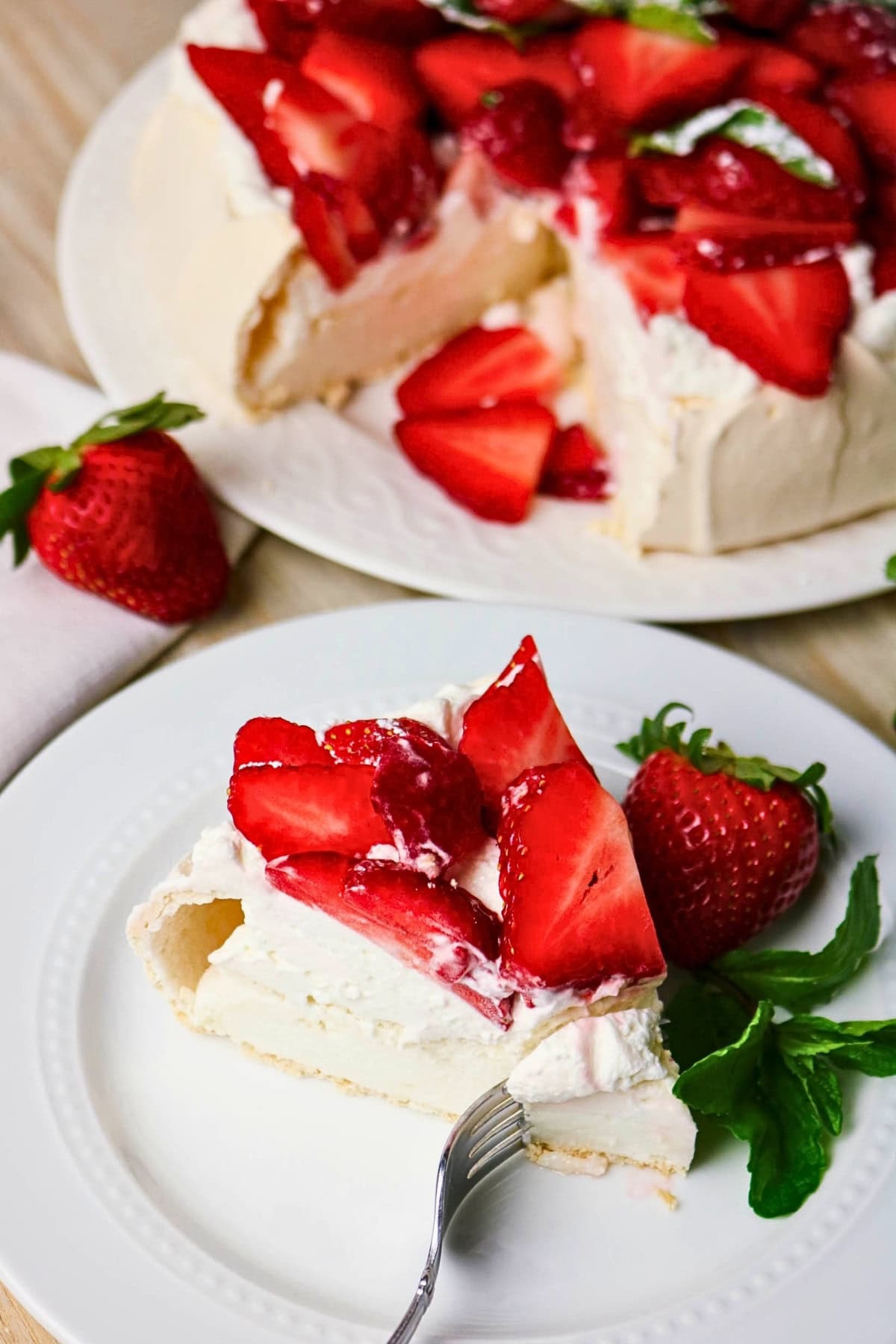 A slice of strawberry pavlova on a plate, garnished with fresh strawberries.