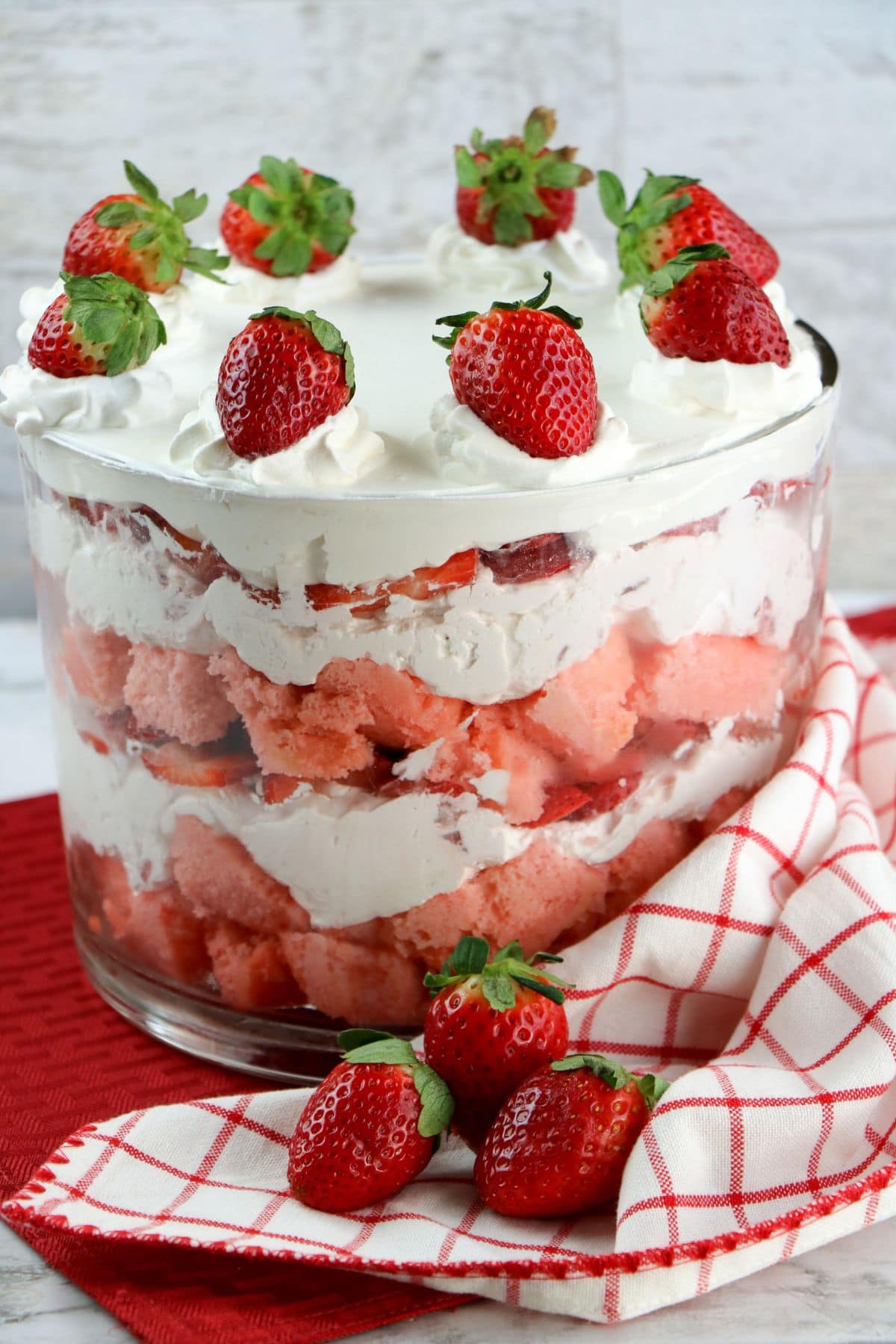 A layered strawberry trifle with whipped cream, topped with whole strawberries.