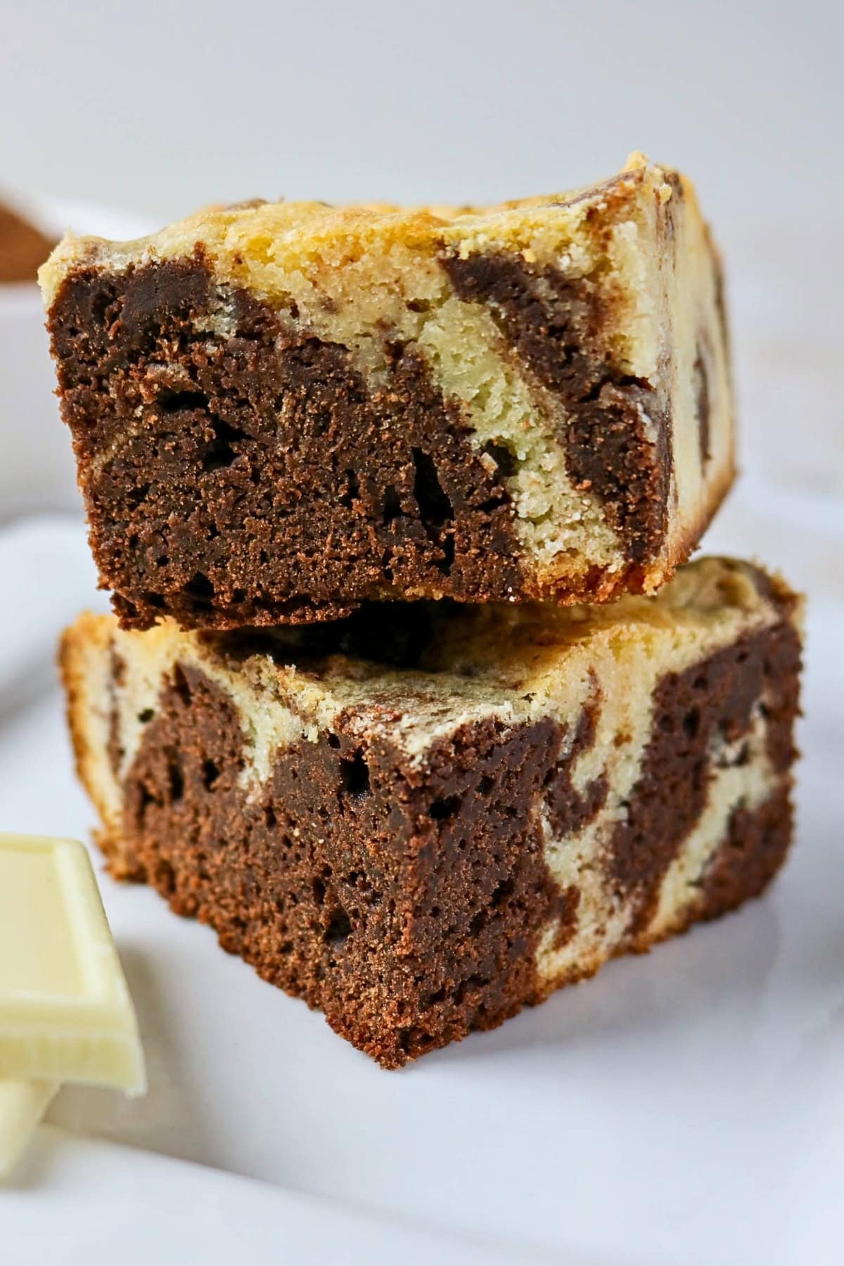 Two stacked marble brownies with swirls of chocolate and vanilla on a white surface.