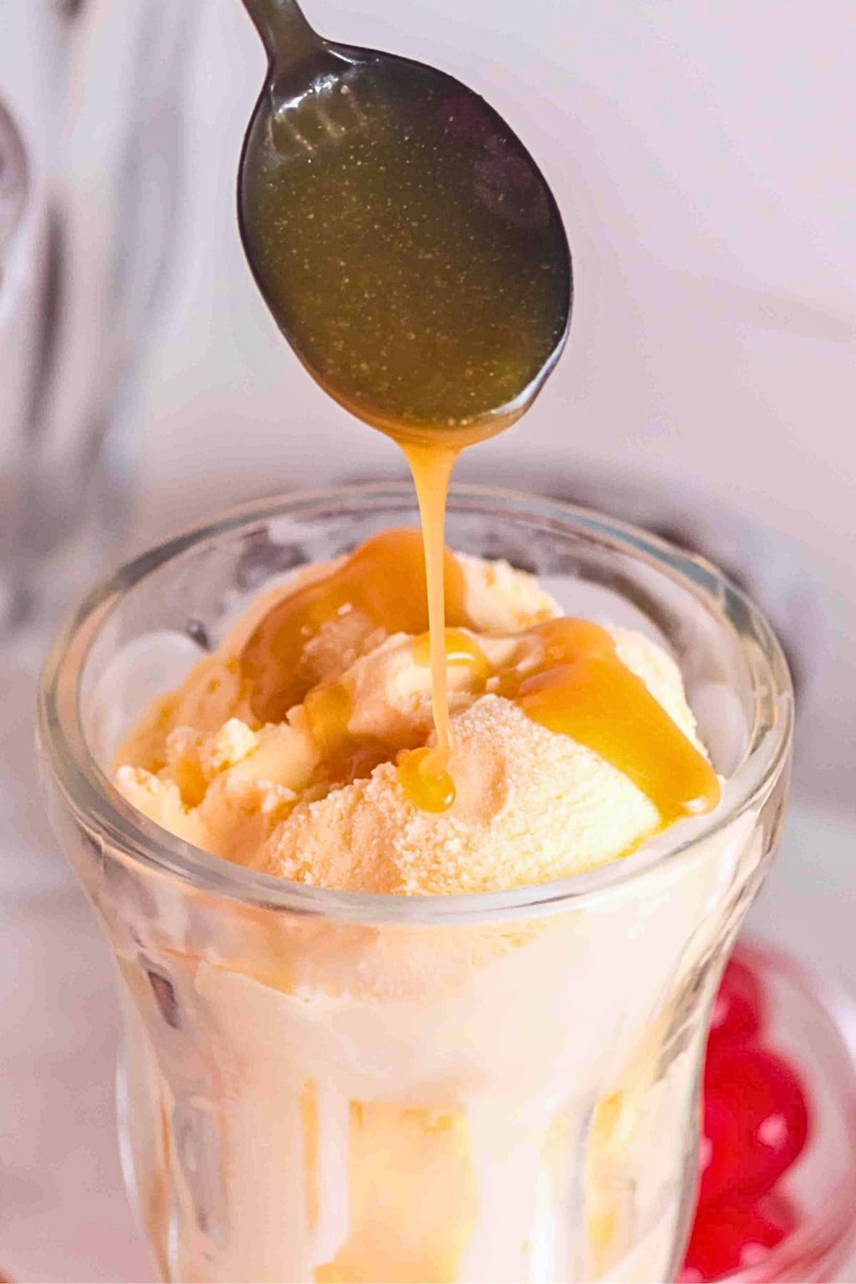 Caramel sauce being drizzled over vanilla ice cream in a glass cup.