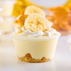 A banana pudding cup topped with whipped cream, banana slice, and cookie crumbs.