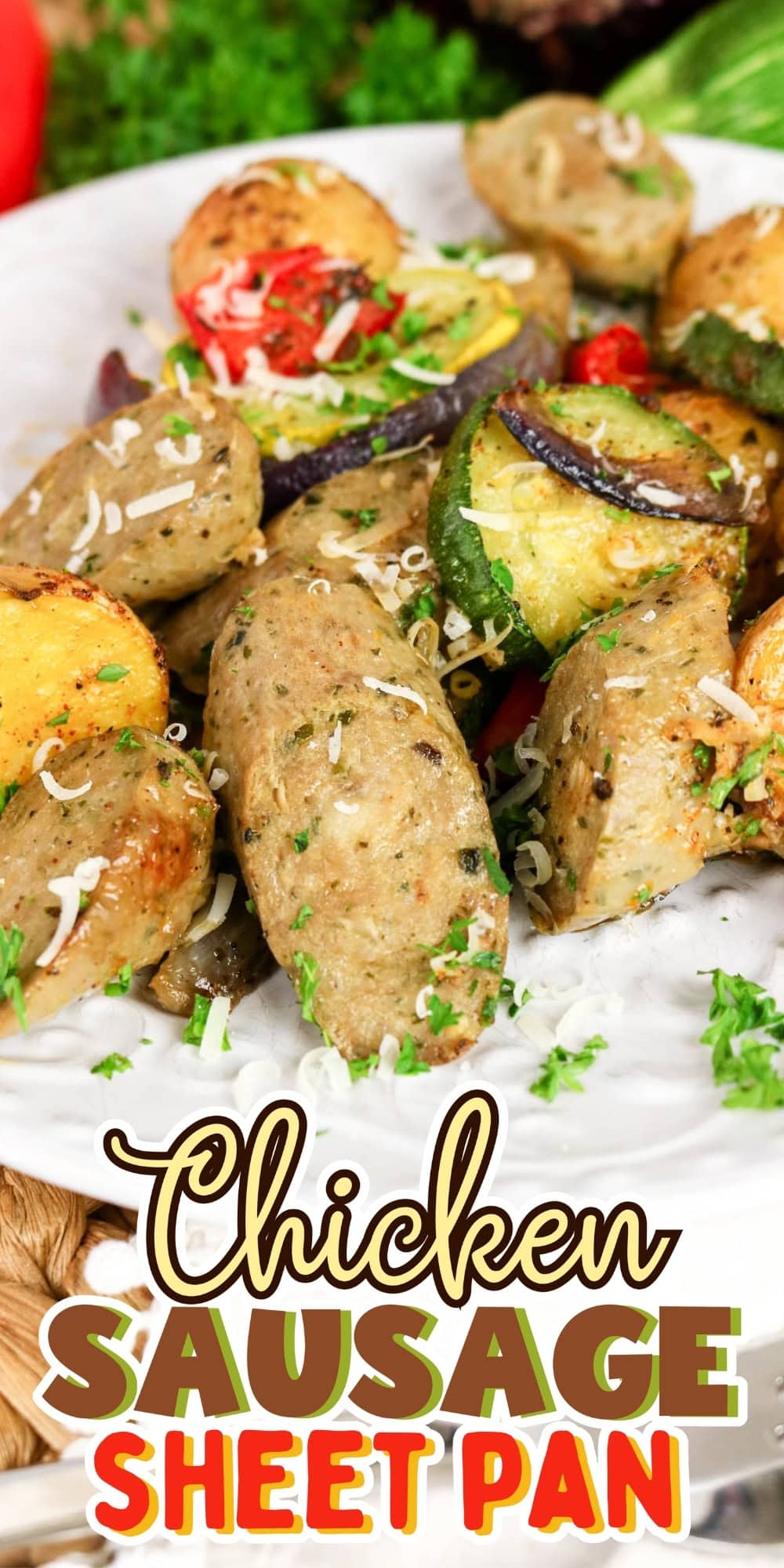 Chicken sausage with roasted vegetables on a white plate, garnished with herbs.