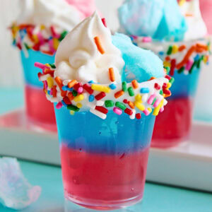 Red and blue layered dessert with whipped cream, sprinkles, and cotton candy.