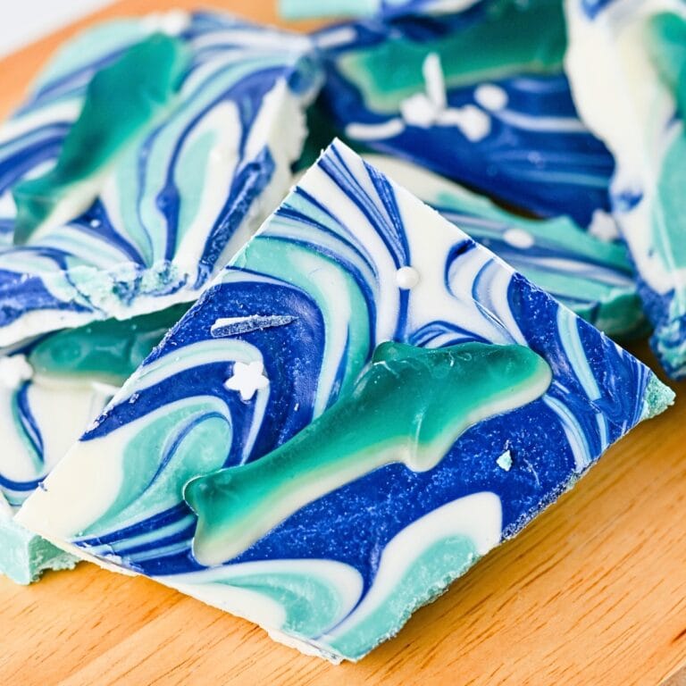 White and blue swirled candy bark with gummy sharks on top, on a wooden surface.