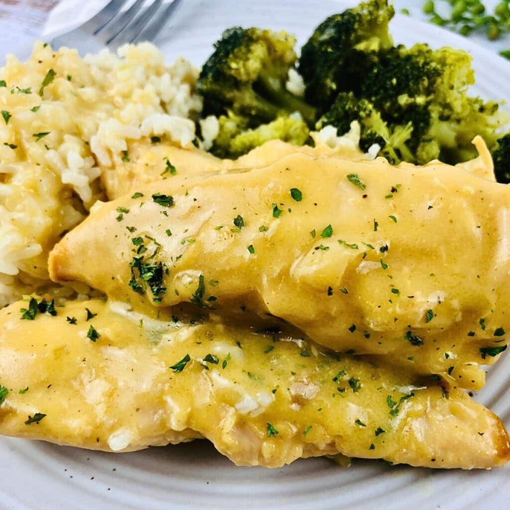 Chicken with creamy sauce, rice, and broccoli on a plate.