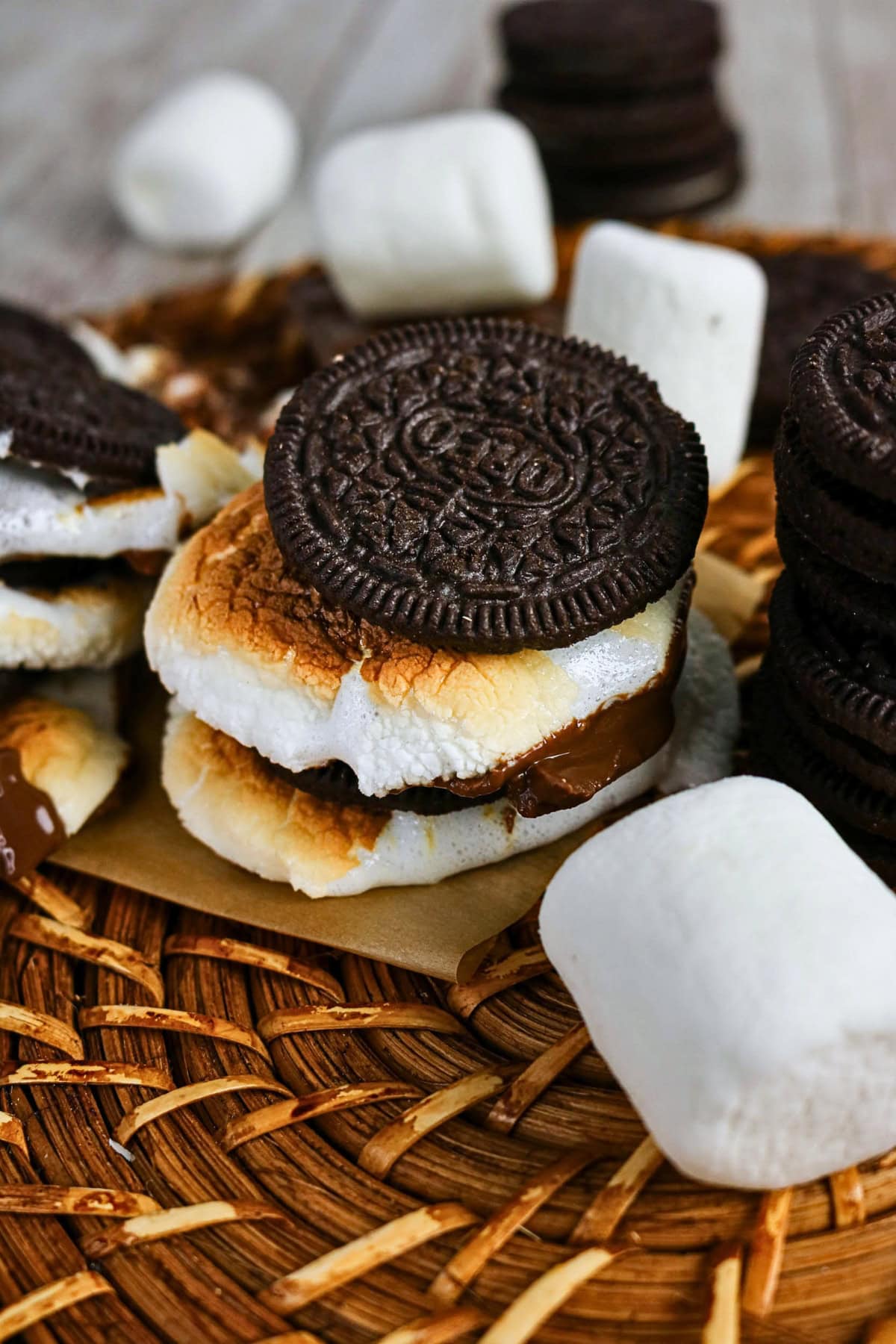 Toasted marshmallow and chocolate sandwiched between Oreo cookies on a mat.