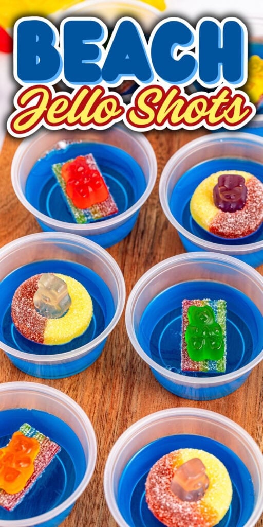 Six blue jello shots with candy decorations on a wooden surface.