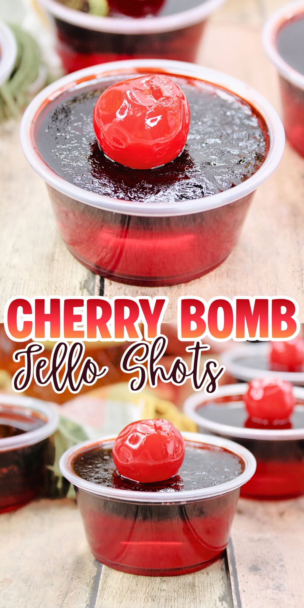 A cherry-topped red jello shot in a clear plastic cup on a wooden surface.