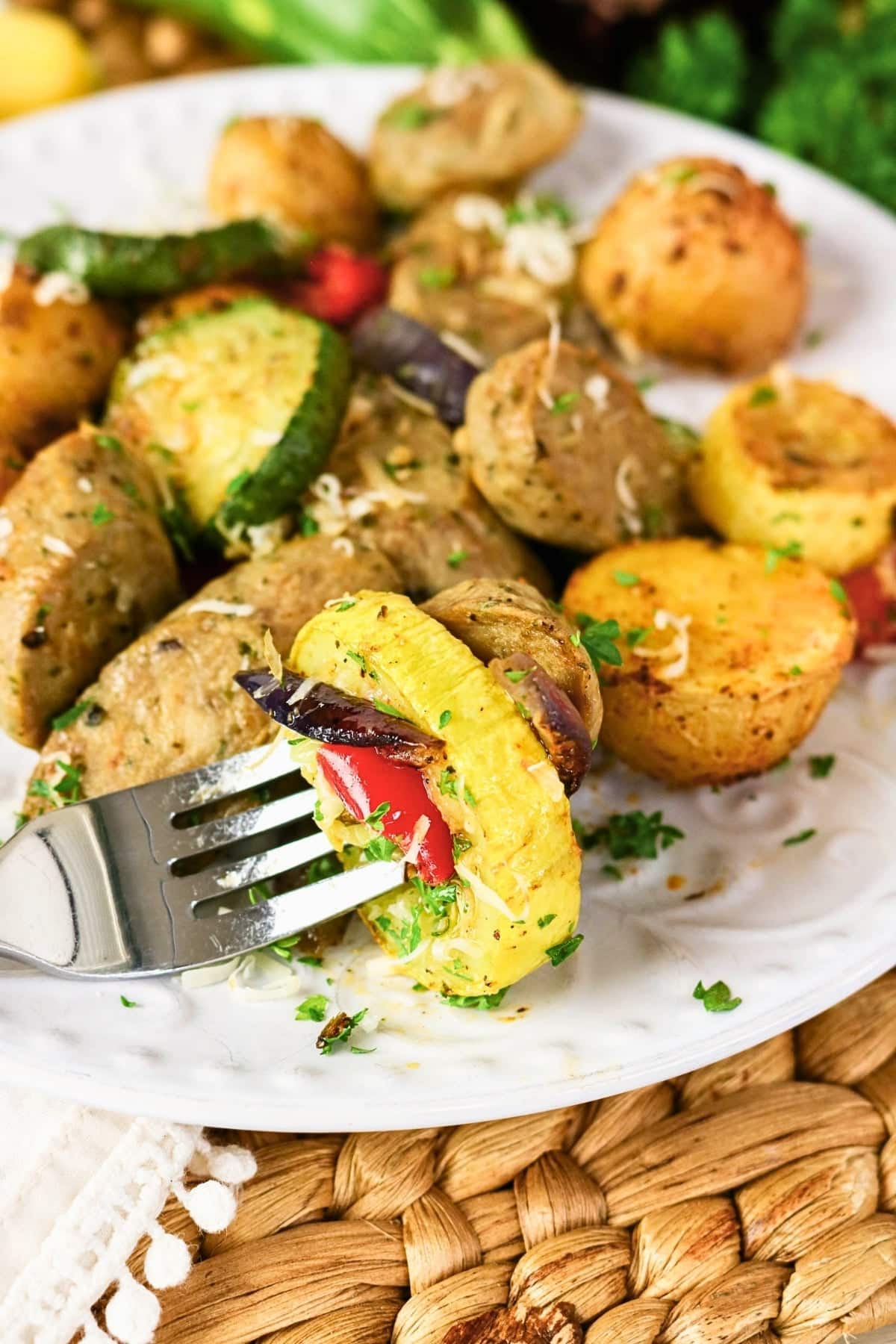 Roasted potatoes, zucchini, squash, red pepper, and herbs on a white plate.