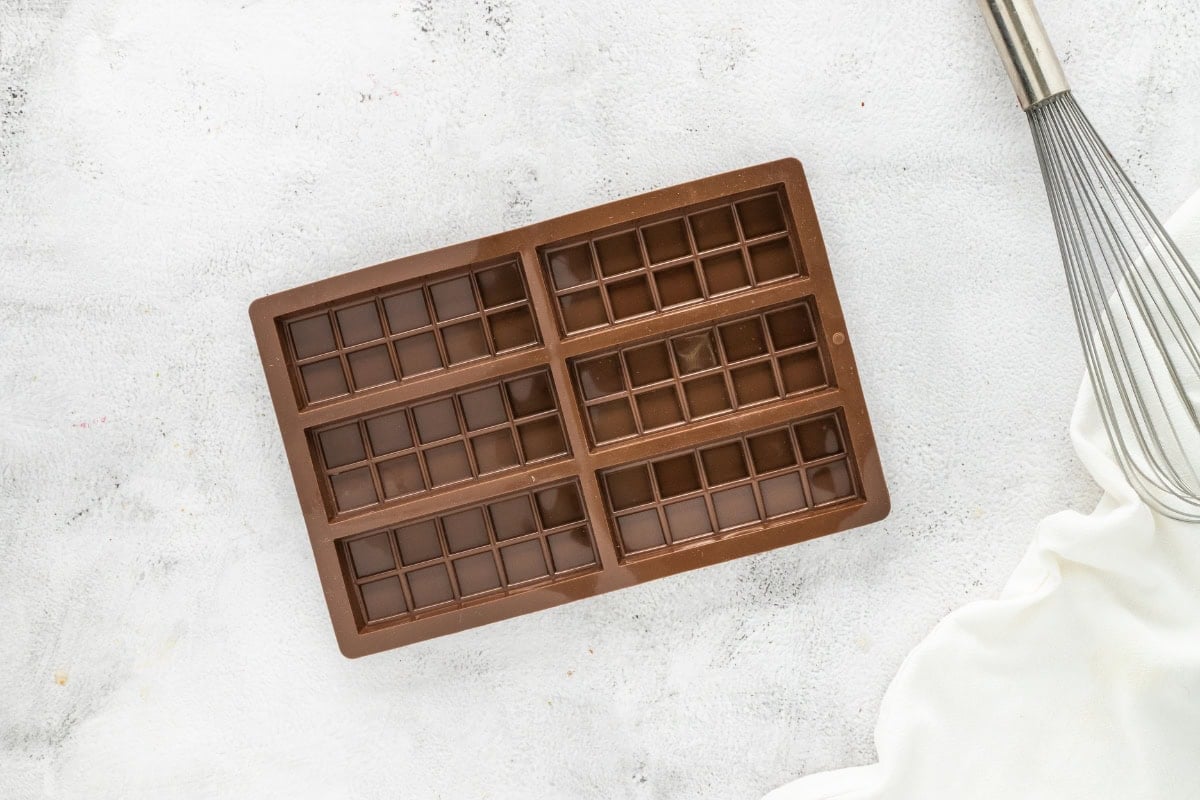 Brown silicone chocolate bar mold with six sections on a white surface.