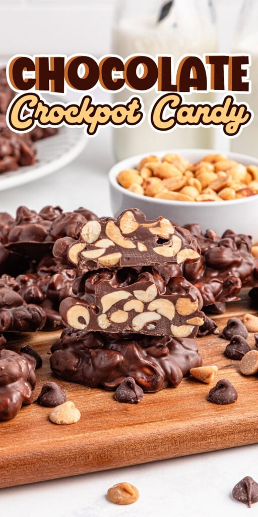 Chocolate crockpot candy with peanuts stacked on a wooden board.