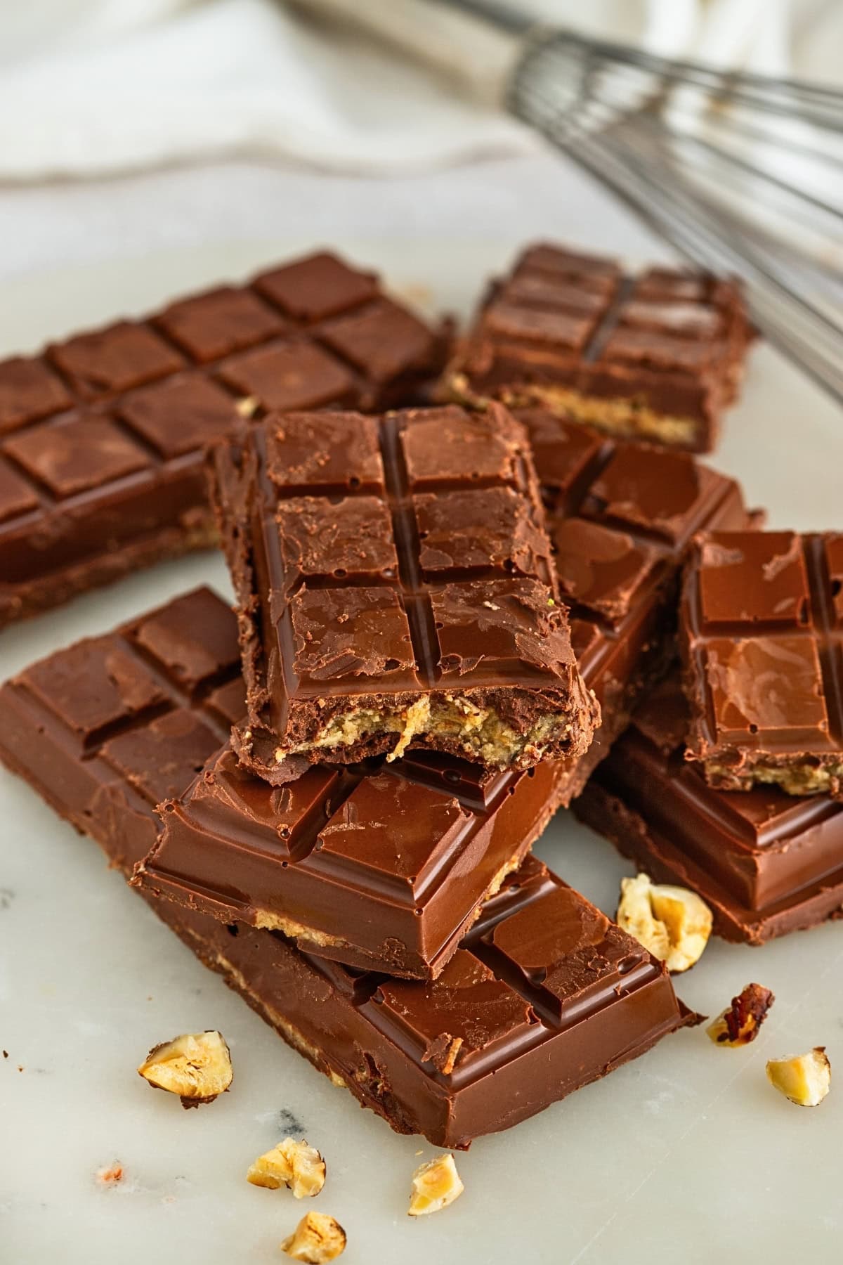 Stacked chocolate bars with visible hazelnut filling and scattered hazelnuts.