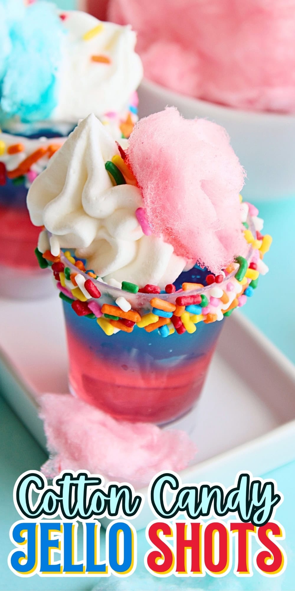 Colorful jello shots topped with whipped cream, sprinkles, and cotton candy.