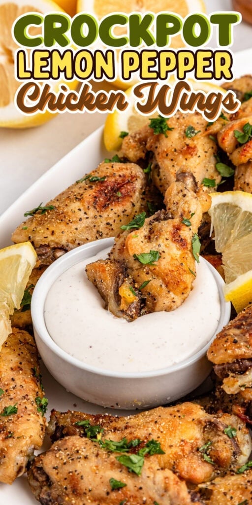 Chicken wings with lemon wedges and dip on a white plate.