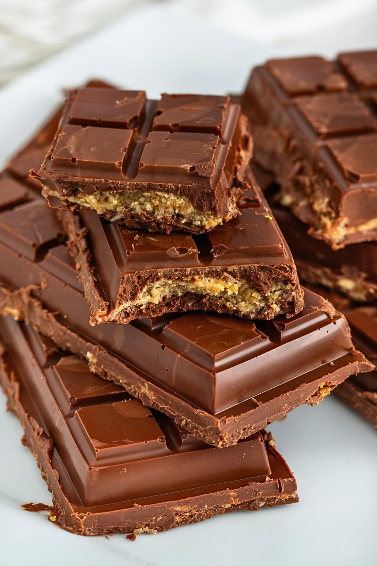 Stack of chocolate bars with a nutty filling, some bars have bites taken out.