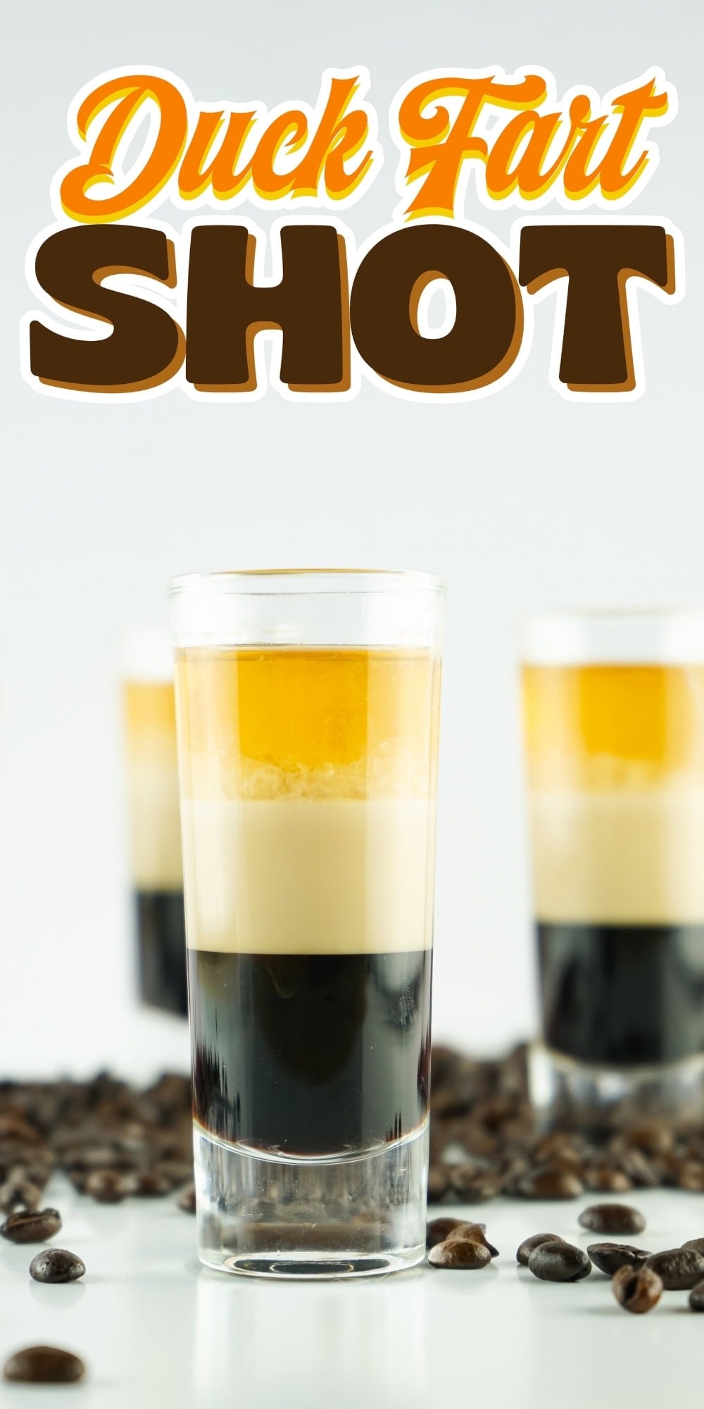 Layered Duck Fart shot in a glass, surrounded by coffee beans.