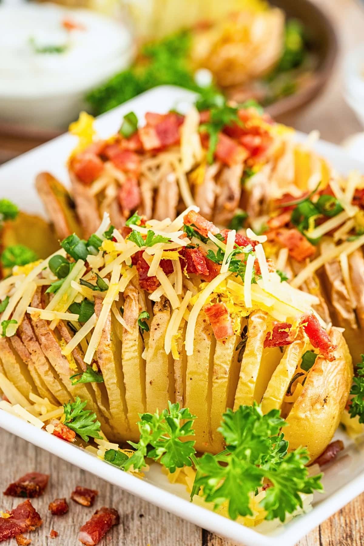 Sliced baked potatoes topped with cheese, bacon, chives, and parsley.