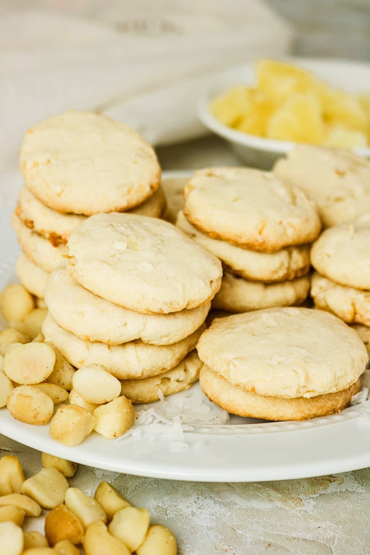Stacks of cookies with macadamia nuts and pineapple pieces on a white plate.