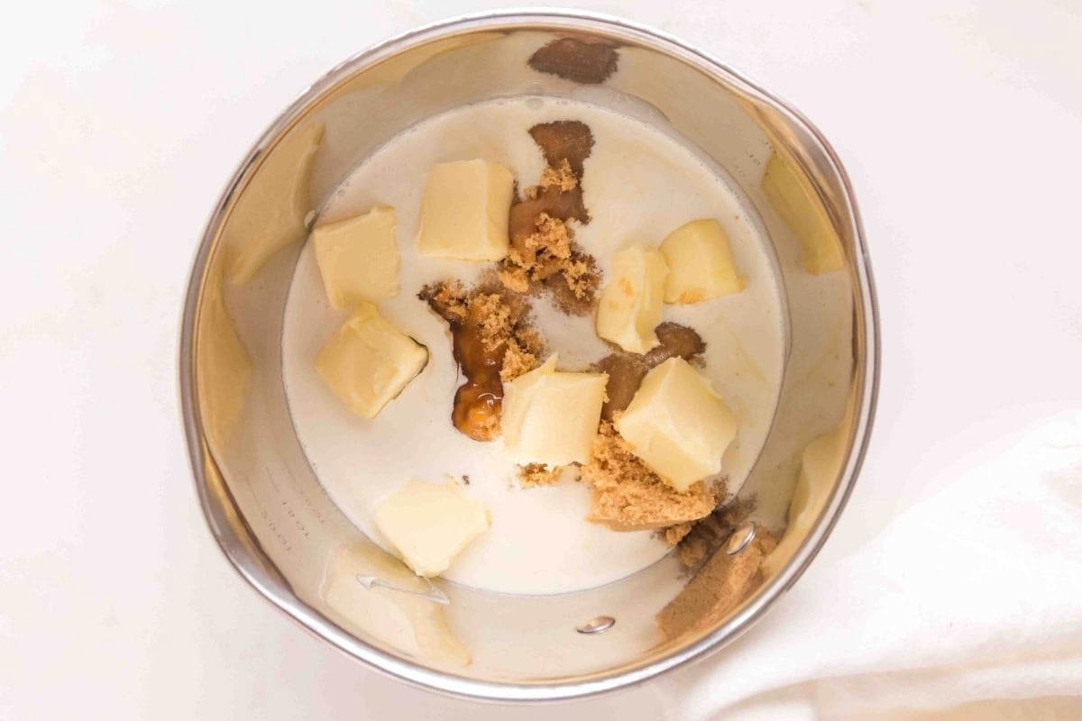Butter, brown sugar, and cream in a metal saucepan, viewed from above.