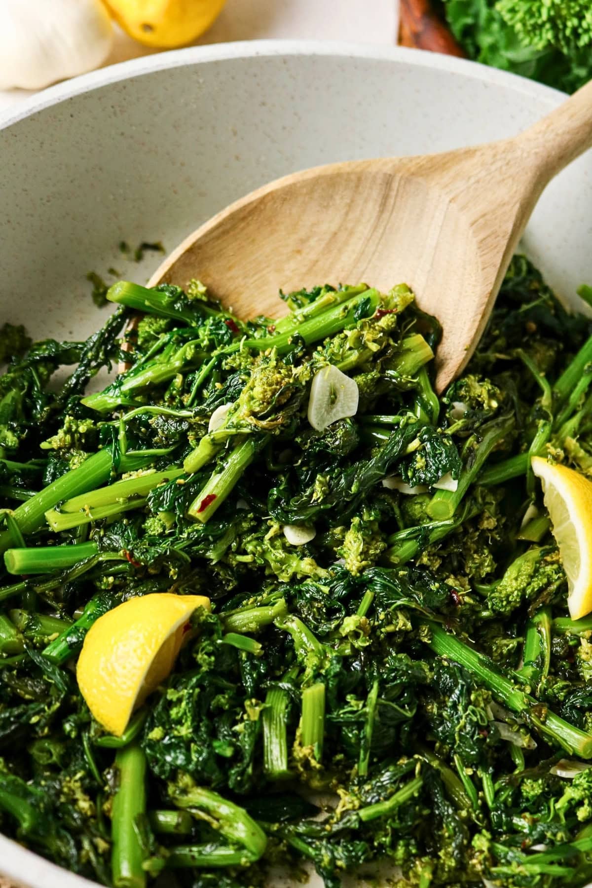 Rapini saut&eacute;ed with garlic and lemon, stirred in a pan with a wooden spoon.