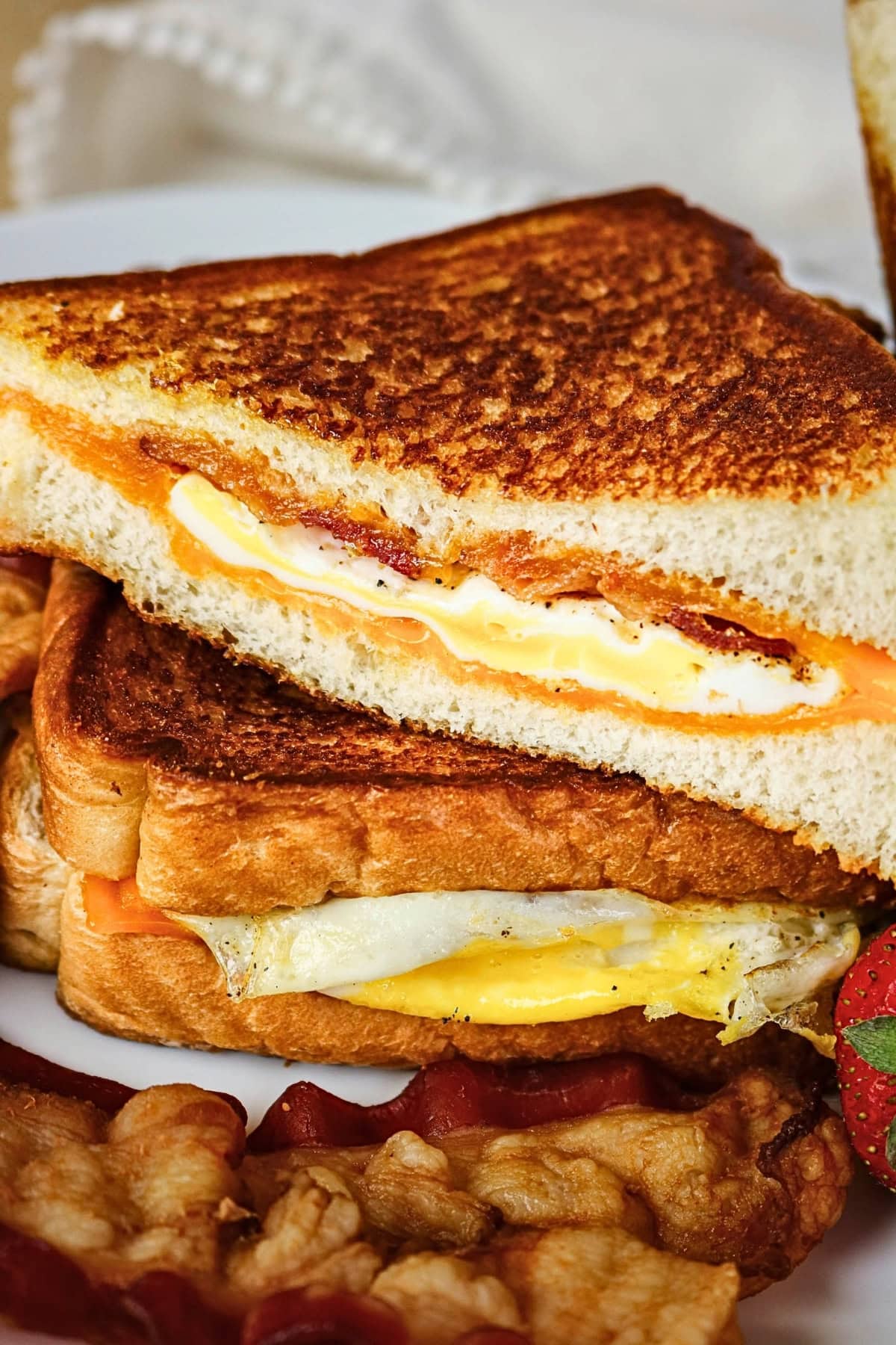 Grilled cheese sandwich with egg and bacon, served with strips of bacon.